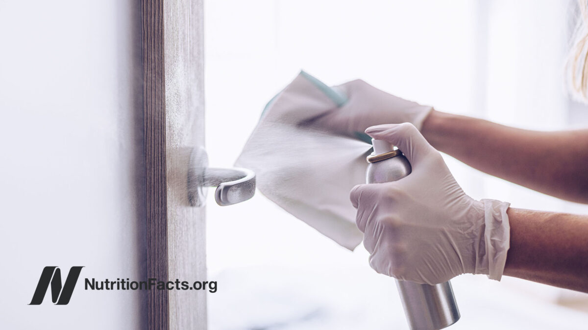person spraying cleaner on door handle