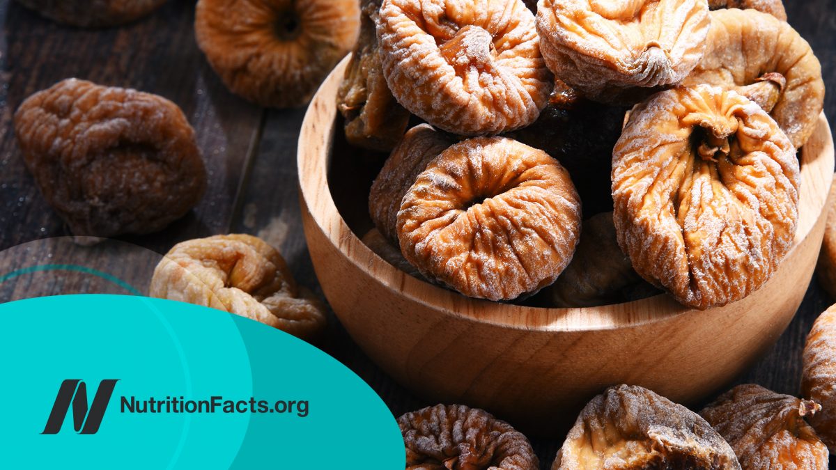 Composition with bowl of dried figs on wooden table