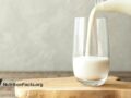 milk poured from a bottle into a glass cup on a wooden stand