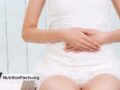 woman sitting while holding stomach