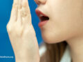Person holding hand in front of mouth breathing out