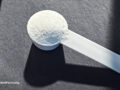 Creatine powder with natural beige background and props