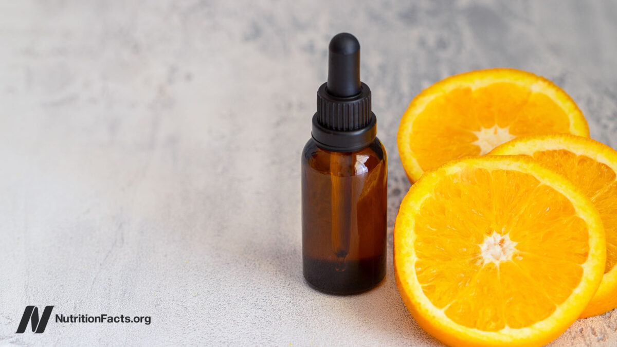 Fresh orange fruit and orange essential oil on concrete background