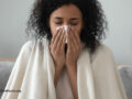 Woman sneezing into a tissue